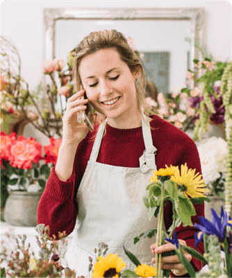 A florist smiling on the phone in her flower shop