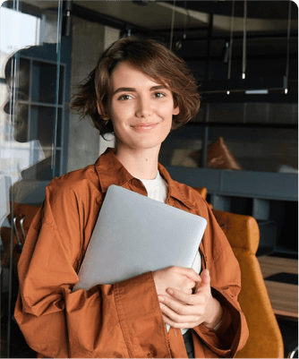 A young professional holding a laptop in a modern office