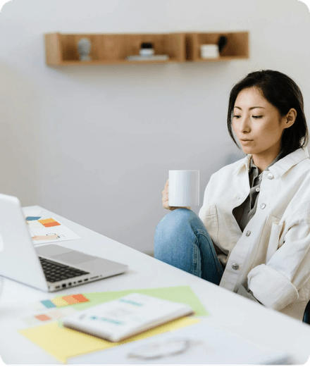 Une fondatrice, une tasse à la main, travaille sur son ordinateur portable