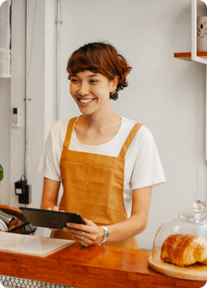 Smiling café owner holding a tablet behind the counter
