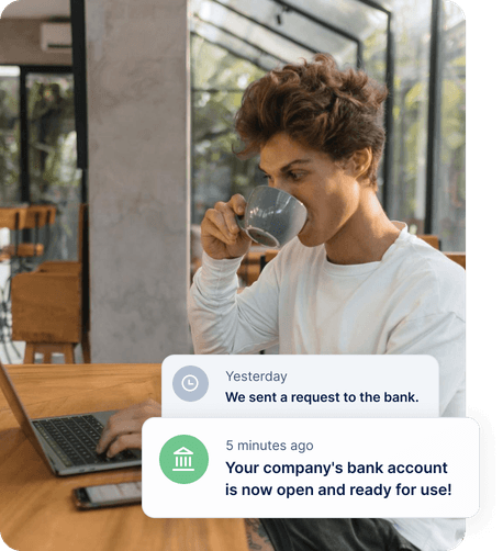A founder drinking coffee at his laptop. EasyBiz notifications: “We sent a request to the bank.” and “Your company’s bank account is now open and ready for use!”