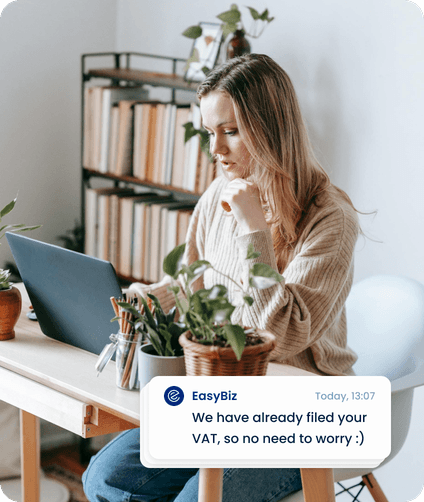 A founder working on her laptop; EasyBiz chat: “We have already filed your VAT, so no need to worry :)”