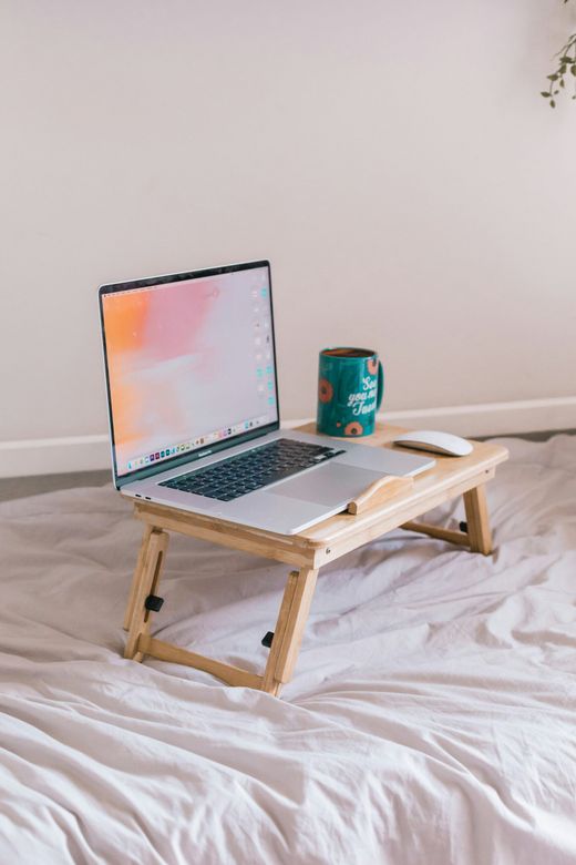 A laptop and a mug on a bed tray