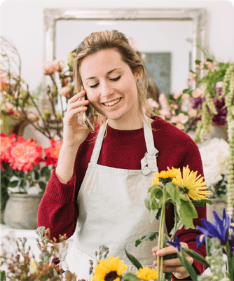 Une fleuriste souriante au téléphone dans sa boutique